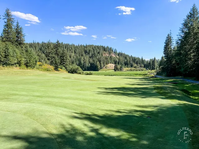 A green and flagstick at The Idaho Club, with a bunker in front and the lake behind the hole.