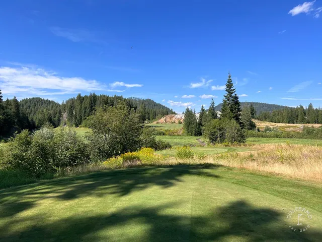 A golfer putting on a green at The Idaho Club, with pines and the lake beyond.