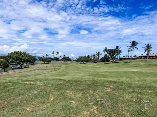 A wide view at the Royal Course, with sand bunkers and the ocean on the horizon.