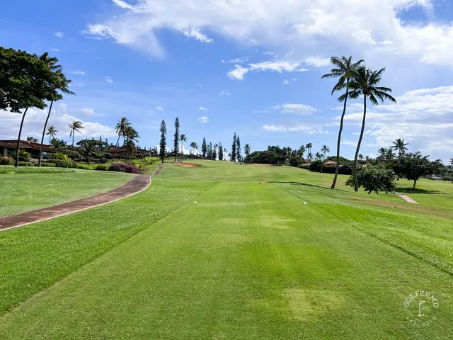 A golfer hitting a tee shot at the Royal Course, with the fairway and ocean ahead.