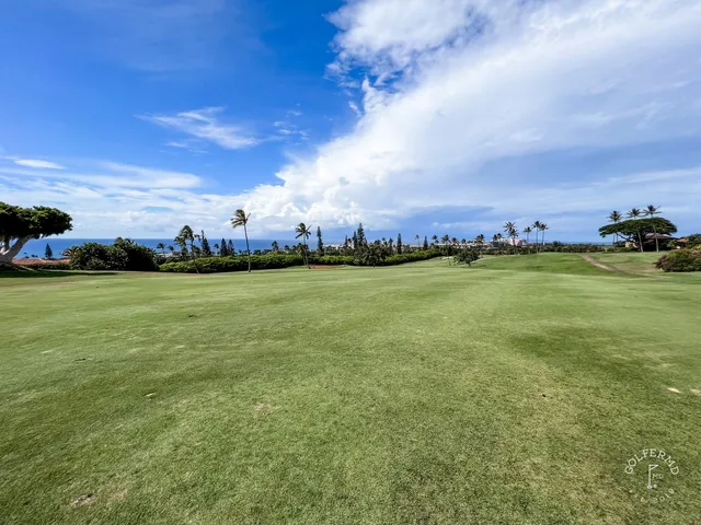 A green and flagstick at the Royal Course, seen across a bunker, with the water behind the hole.