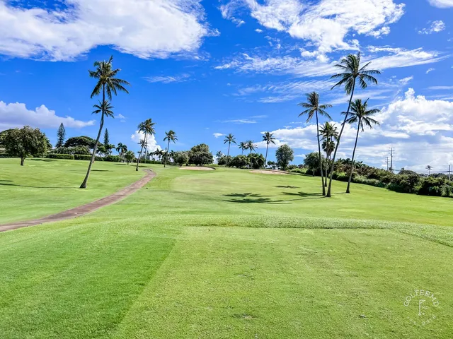Golfers on a fairway at the Royal Course, with the ocean in the distance.