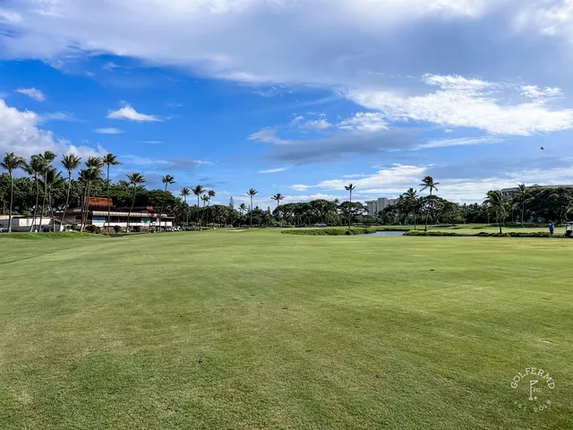 A fairway and green at the Royal Course, with the coast on the horizon.