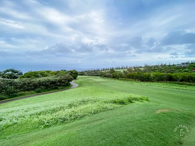 A green and flagstick at the Plantation Course, with a sand bunker and the Pacific behind the hole.