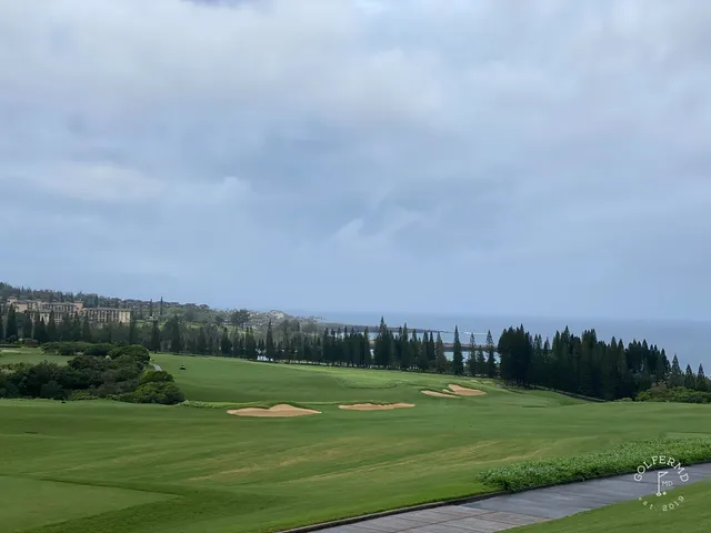 A fairway at the Plantation Course with a sand bunker in the foreground and the ocean in the distance.
