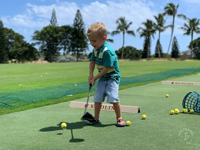A green and flagstick at Ko Olina, with the ocean and a rocky shoreline behind the hole.