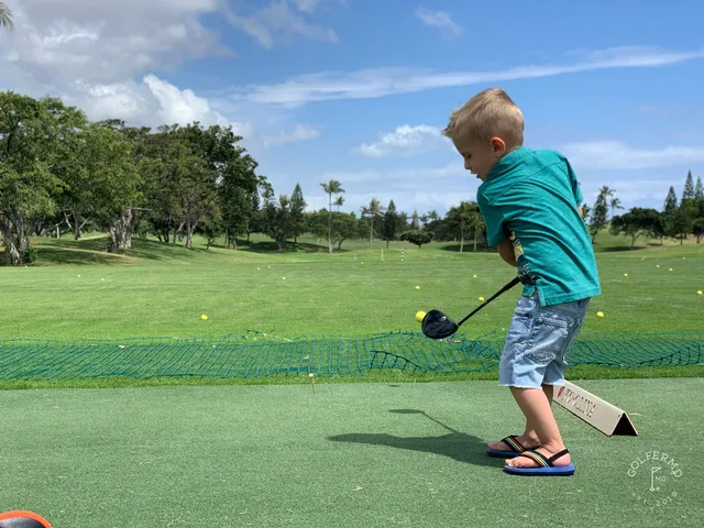 A green and flagstick at Ko Olina, with a pond beside the green and palm trees along the water.