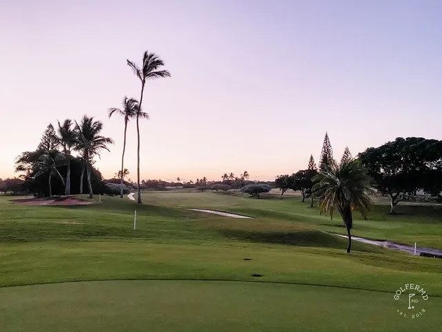 A green and flagstick at Ko Olina, with lava rock and the ocean behind the hole.