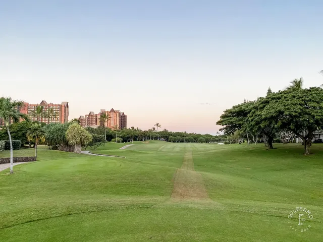 A green and flagstick at Ko Olina, with a sand bunker in front and the ocean behind the hole.