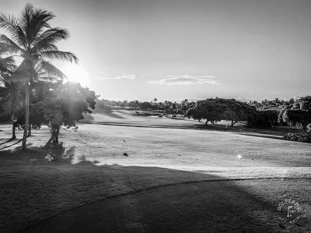 A green and flagstick at Ko Olina, with lava rock in the foreground and the ocean behind the hole.