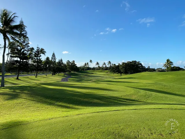 A green and flagstick at Ko Olina, seen from a rise, with the ocean behind the hole.