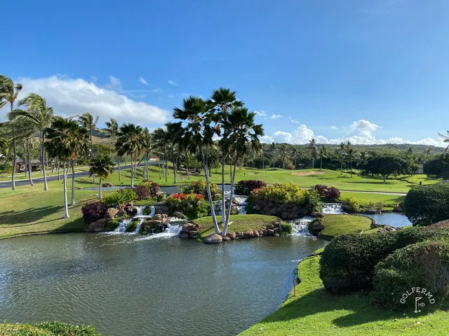 A green and flagstick at Ko Olina, with palm trees and the ocean behind the hole.