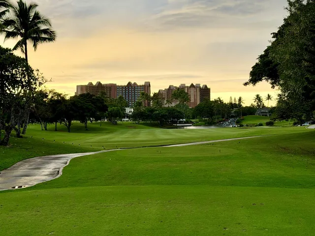 A golfer hitting a tee shot at Ko Olina, with the fairway and ocean ahead.