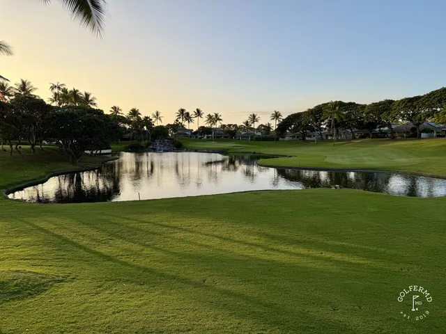 A fairway at Ko Olina lined with palm trees, with a pond along the right side.