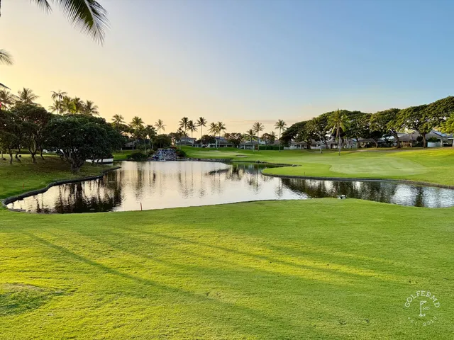 A green and flagstick at Ko Olina, with the ocean and a rocky shoreline behind the hole.
