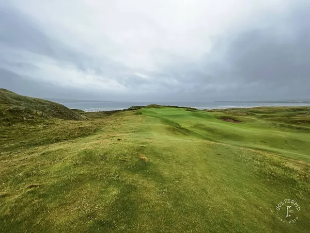 A fairway at Lahinch with a bunker along one side and the Atlantic ahead.