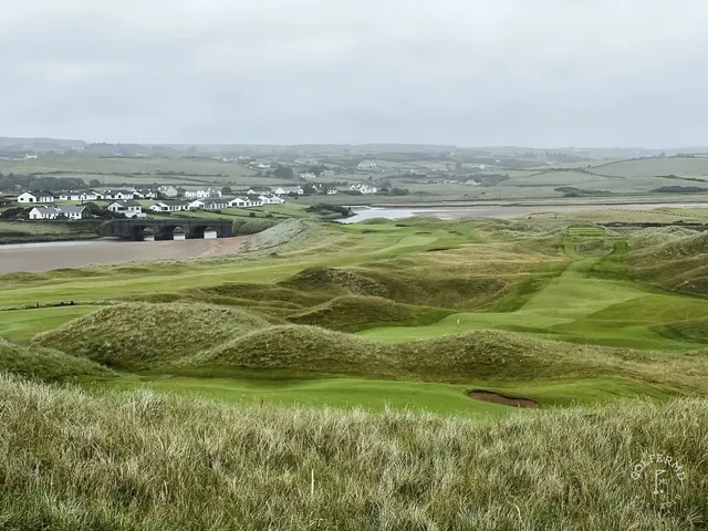 A golfer hitting a shot from the dunes at Lahinch, with the ocean ahead.