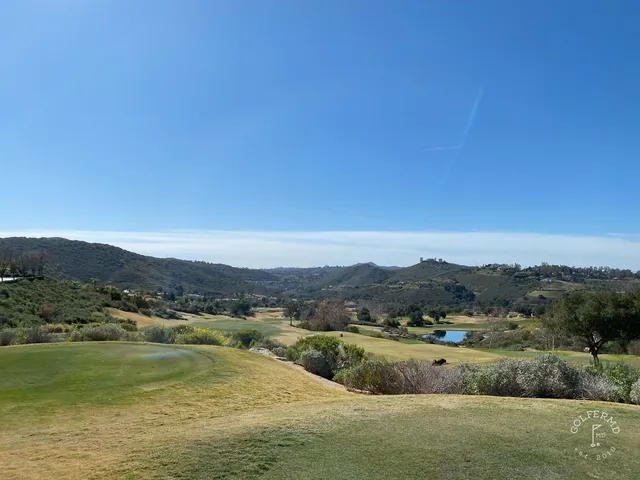 A golfer putting on a green at Maderas Golf Club, with another person nearby and hills behind them.