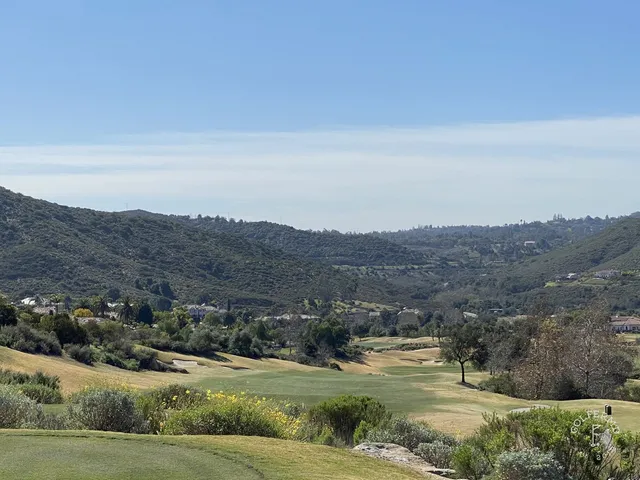 A group posing for a photo on a tee at Maderas Golf Club, with the canyon behind them.