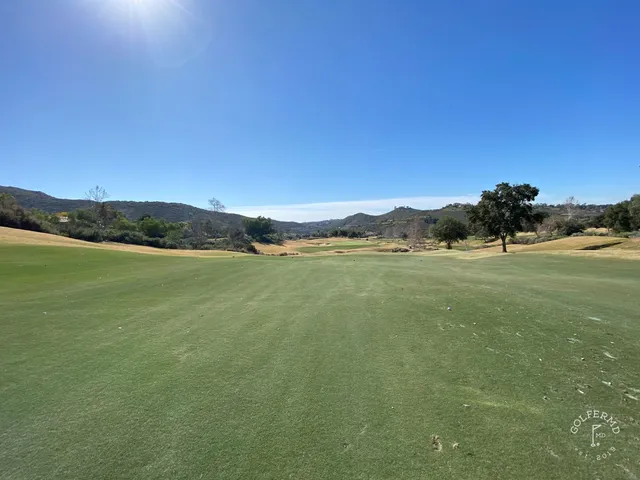 A group posing for a photo at Maderas Golf Club, with the course and hills behind them.