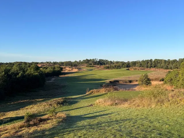 A wide view at Mammoth Dunes, with sandy ground and the fairway stretching ahead.
