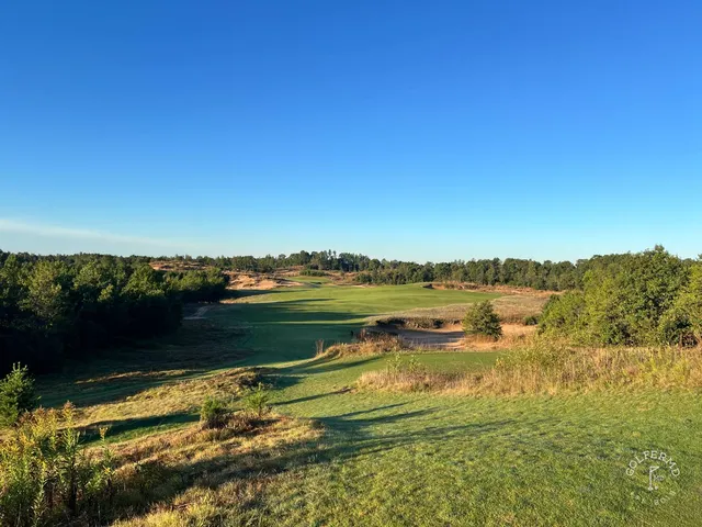 A golfer hitting a shot at Mammoth Dunes, with the sandy fairway ahead.