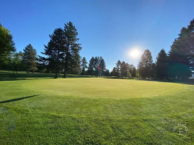 A fairway at Missoula Country Club, with trees along the hole and mountains in the distance.