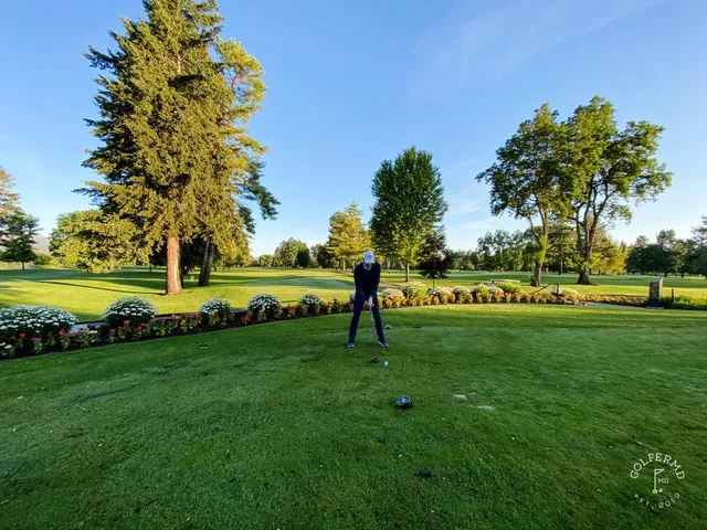A golfer hitting a shot at Missoula Country Club, with the fairway and mountains ahead.