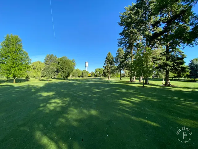 A fairway at Missoula Country Club lined with trees, running toward the mountains.