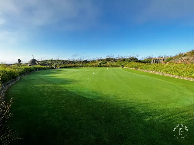 A green and flagstick at Old Head, with the ocean far below the green.