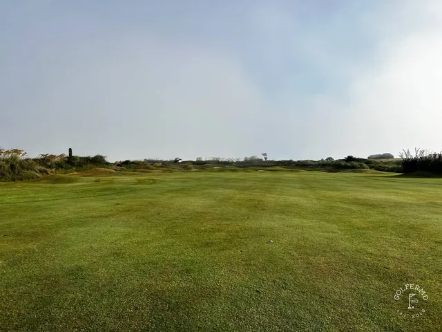 A golfer hitting a shot at Old Head, with the cliff and the ocean ahead.