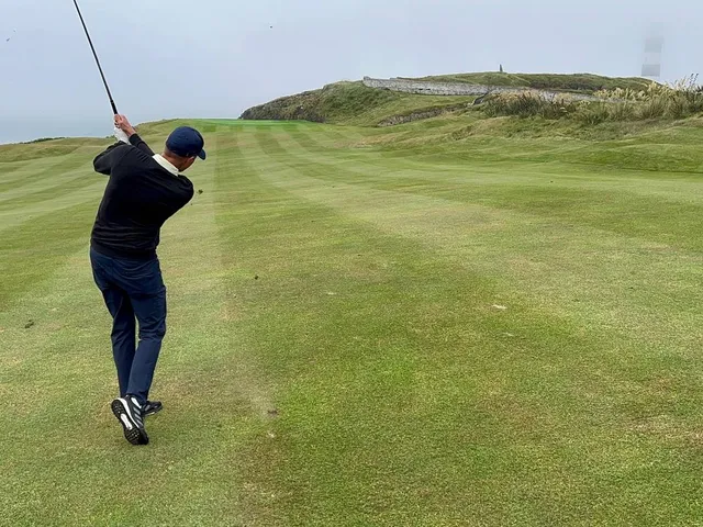 A green and flagstick at Old Head perched above the water.
