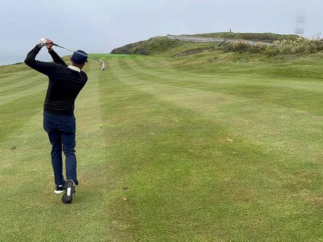 Golfers on a tee at Old Head, with the ocean behind them.