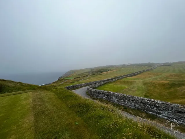 A close view of a flagstick at Old Head, with the Atlantic below the green.