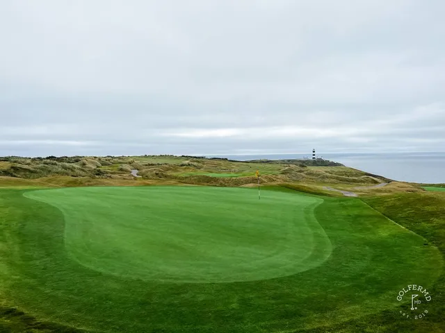 A green and flagstick at Old Head, with a deep bunker in front and the ocean beyond.