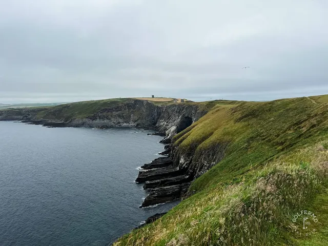 A fairway at Old Head bending along the cliff toward the lighthouse.