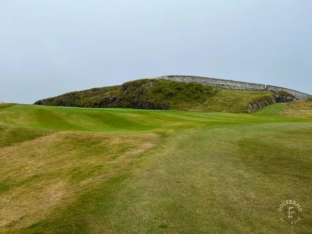 A close view of a flagstick at Old Head, with the cliffs behind the green.