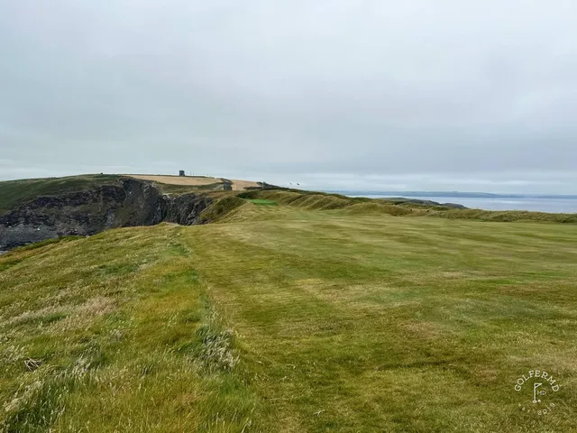 A green and flagstick at Old Head high above the waves.