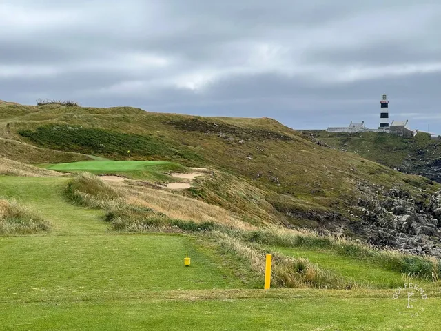 A golfer hitting a tee shot at Old Head, with the Atlantic ahead.
