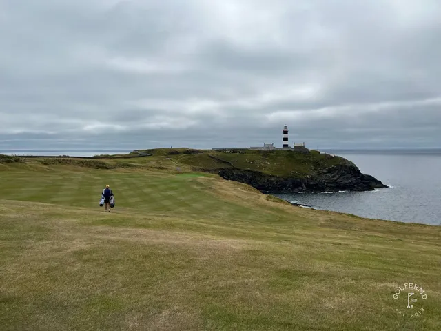 A green and flagstick at Old Head, with the lighthouse in the distance.