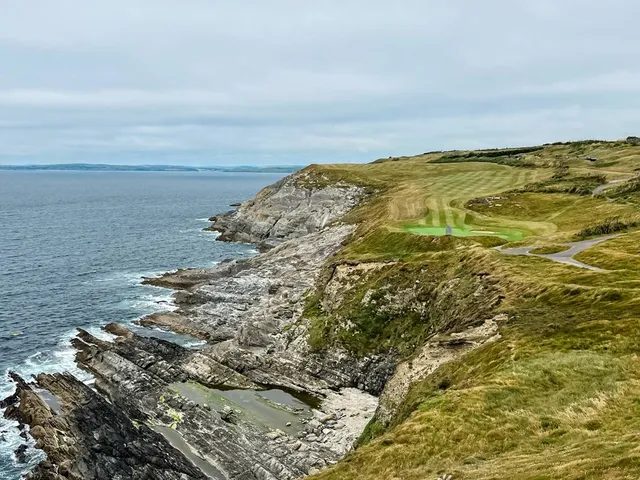 A group of golfers on a green at Old Head, with the cliffs behind them.