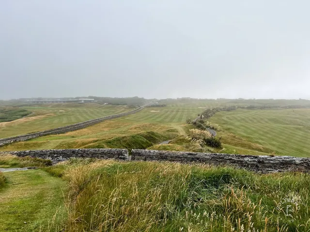 A close view of a flagstick at Old Head, with the cliff and the lighthouse.