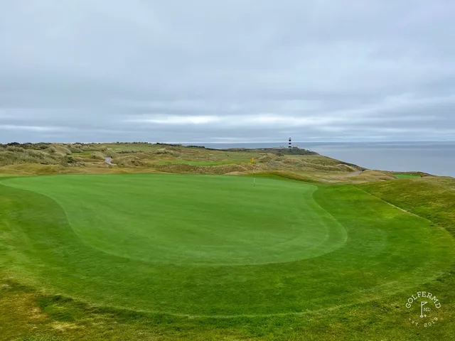 A green and flagstick at Old Head, with sand and the ocean around the hole.