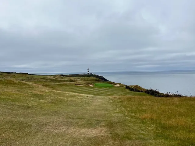 A golfer on the green at Old Head, with the cliff edge behind the hole.