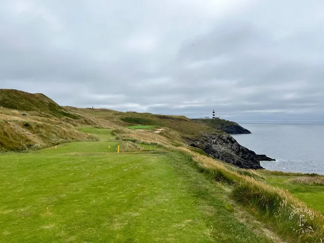 A fairway at Old Head curving back toward the clubhouse, with the water still in view.