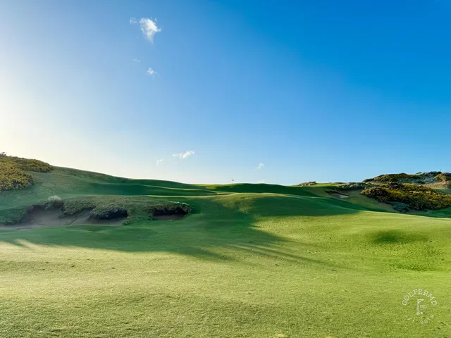 A green at Old Macdonald with the flagstick, fescue around the hole and the Pacific beyond.