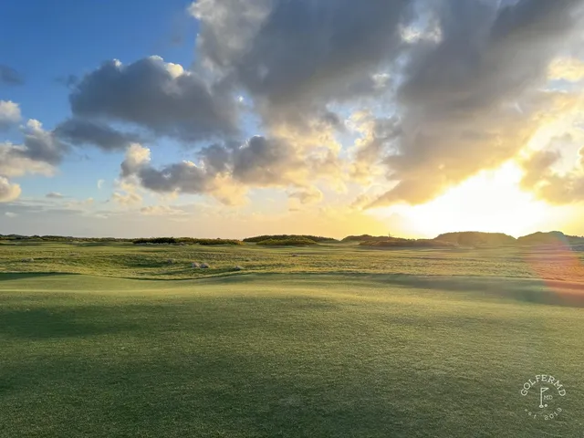 A green and flagstick at Old Macdonald, fescue in the foreground and the Pacific behind the hole.