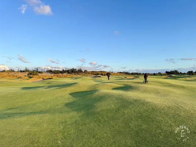 A closer green at Old Macdonald, the flagstick and a deep bunker with the dunes behind.