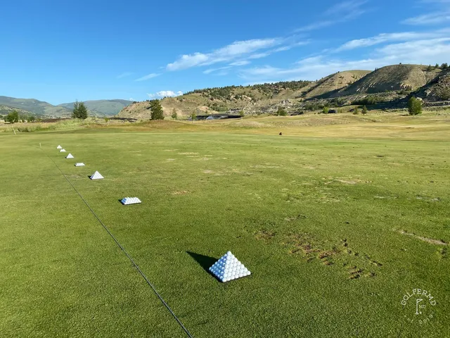 A golfer hitting a shot at Old Works, with the fairway and the mountains ahead.