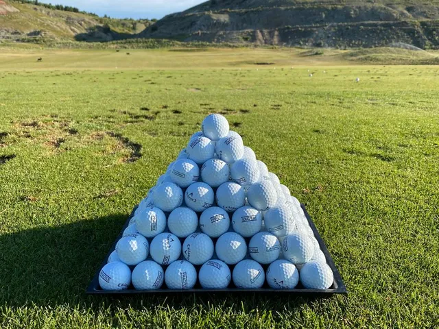 Golfers on a tee at Old Works, with the mountains behind them.